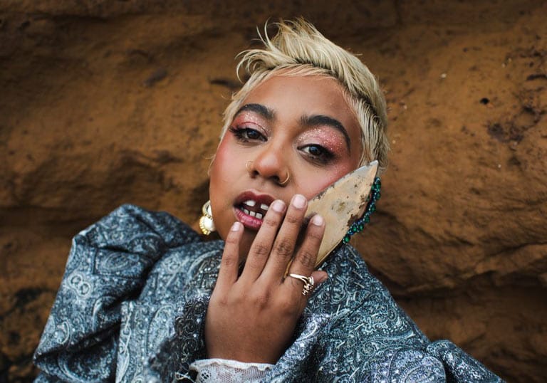 Glamorous portrait of Emily Wurramara photographed in front of a large rock wall