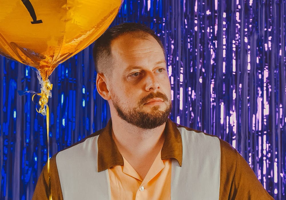 Horrorshow Horrorshow artist, standing with a yellow helium balloon and blue tinsel background