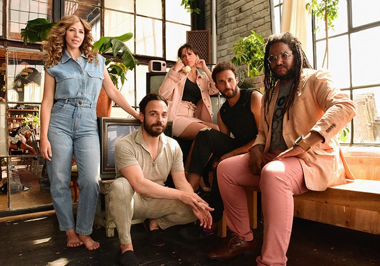 Lake Street Dive in pastel outfits posing in a light filled room