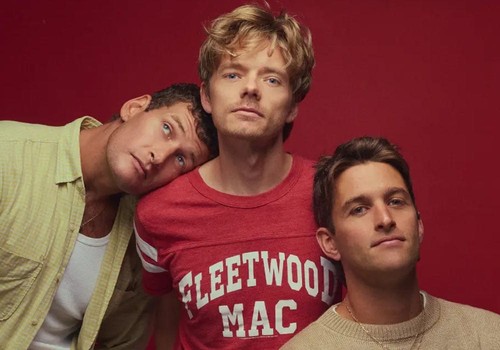 Sons of the East band members standing in front of a red background