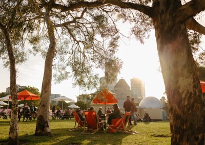 Live at the Gardens with lots of nice chairs and tables. People are enjoying the evening glow of the sun setting.