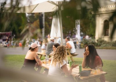 People sitting at a picnic table drinking Archie Rose Gin talking in the Royal Botanic Gardens Melbourne